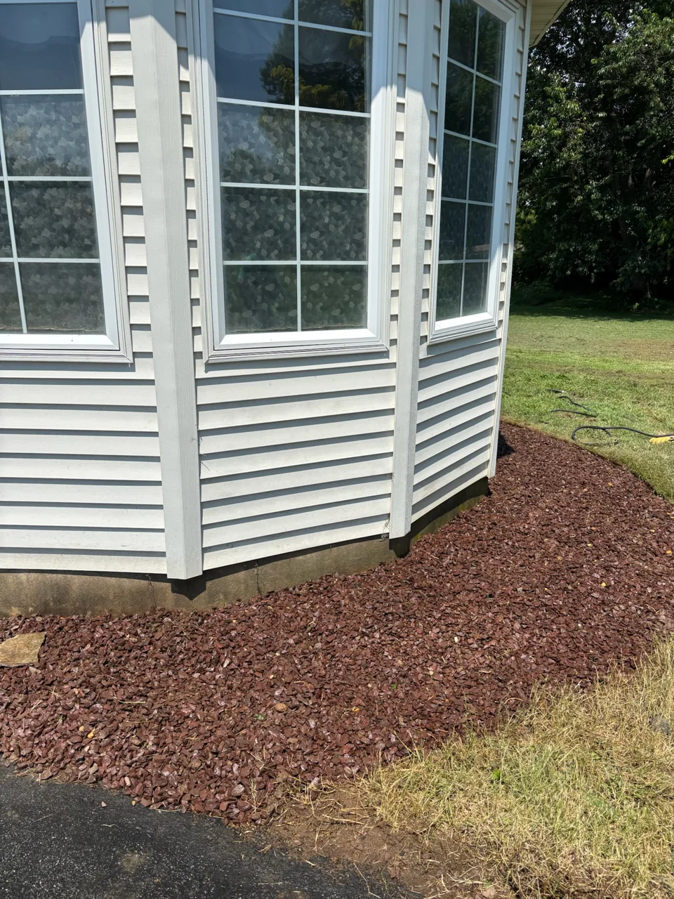 Close view of the finished landscape bed beneath a bay window