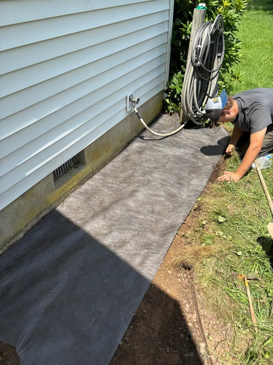 Crew member fitting landscape fabric to the edge of a garden bed